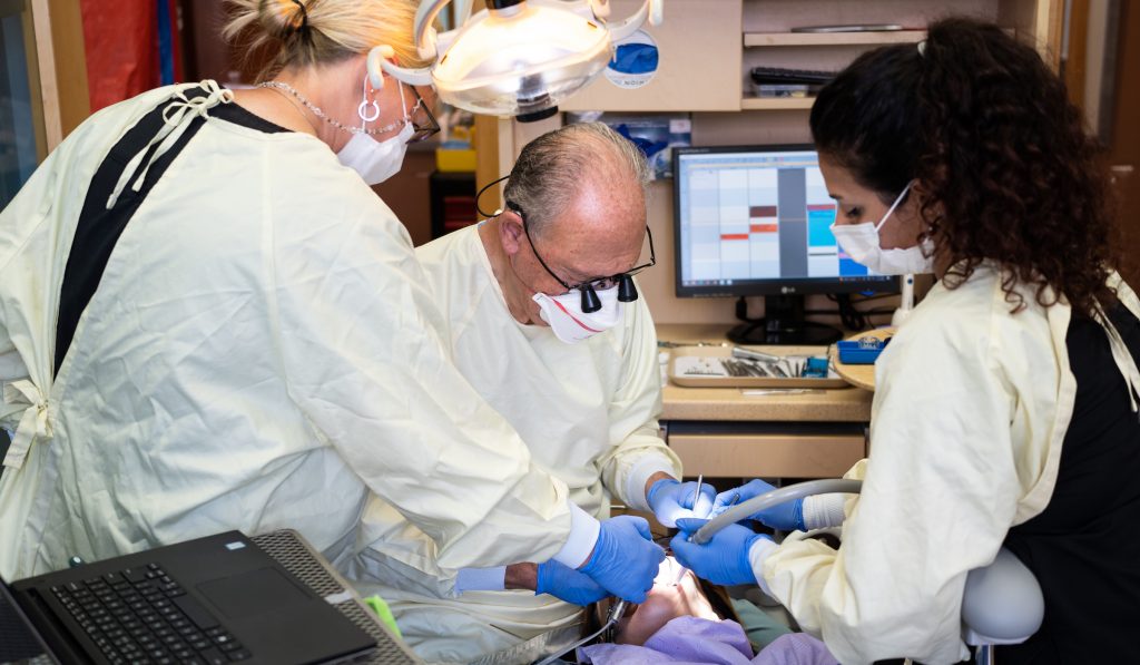 Prosthodontist performing cosmetic procedure on patient.